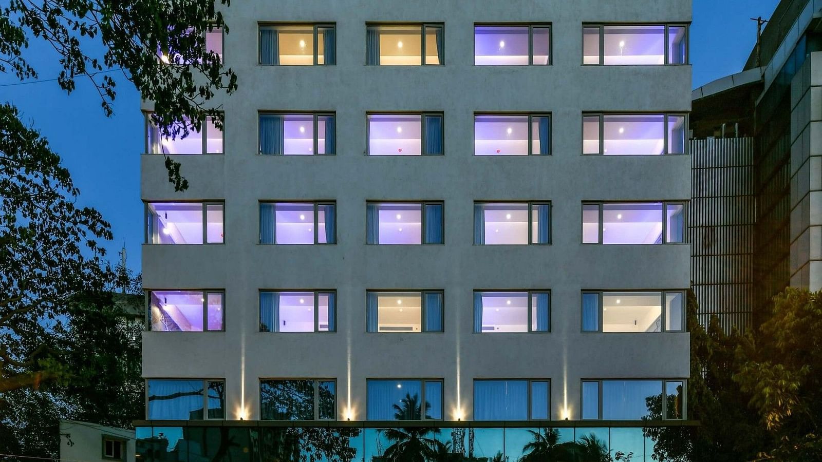A facade view of Indie Stays, BKC Kalina, illuminated against the night sky.