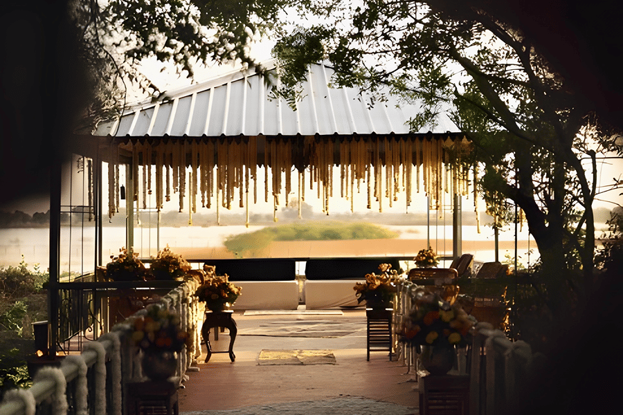 View of lit venue framed by trees at Umaid Palace during Charvi & Dhruv wedding event.