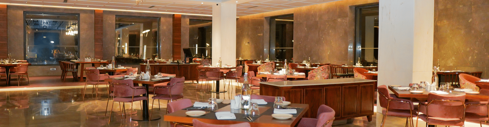 Interior view of the resort restaurant with modern decor, marble floors, and pink seating at Pushkara Resort & Spa.