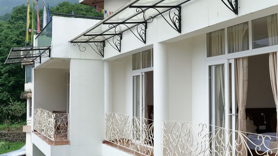 White villas with balconies, a swimming pool, and a foggy mountain view. - VITS Kunjham Retreat, Gangtok