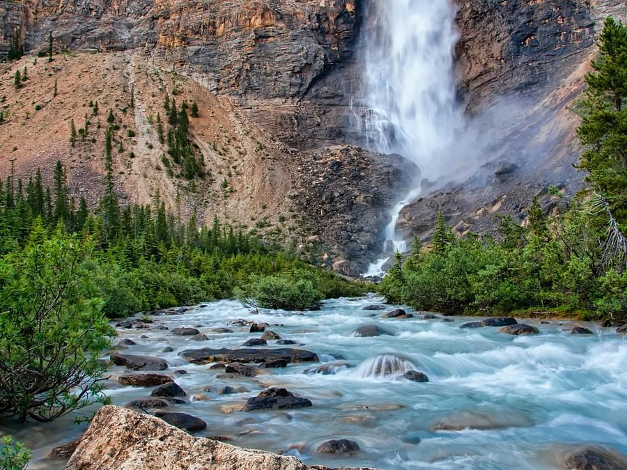 Image of a cascading water fall with rocks all around and rock all around.