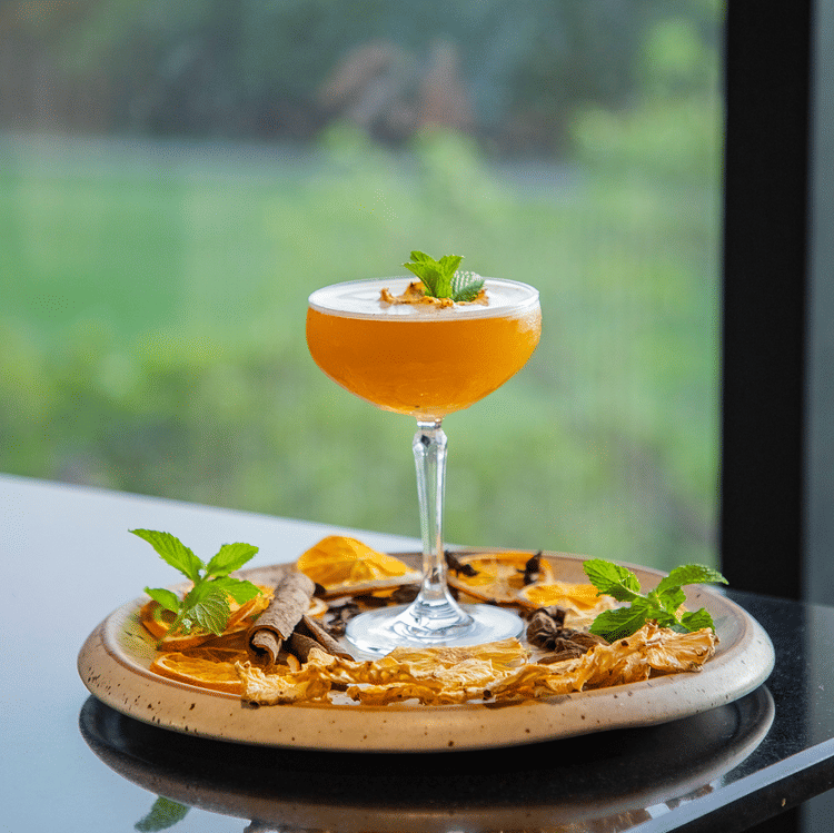 A close up shot of a drink with a pizza below it - Karma Lakelands.