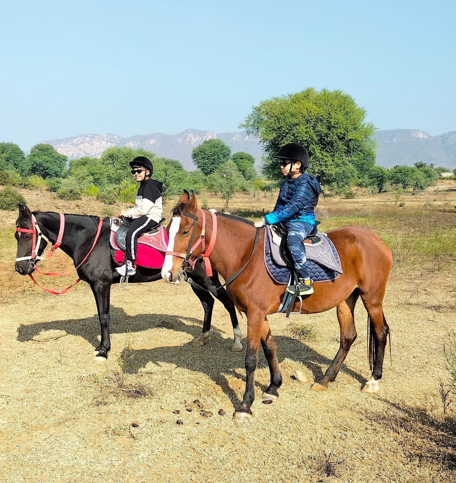 An image of two kids sitting on two separate horses - Utsav Camp Sariska