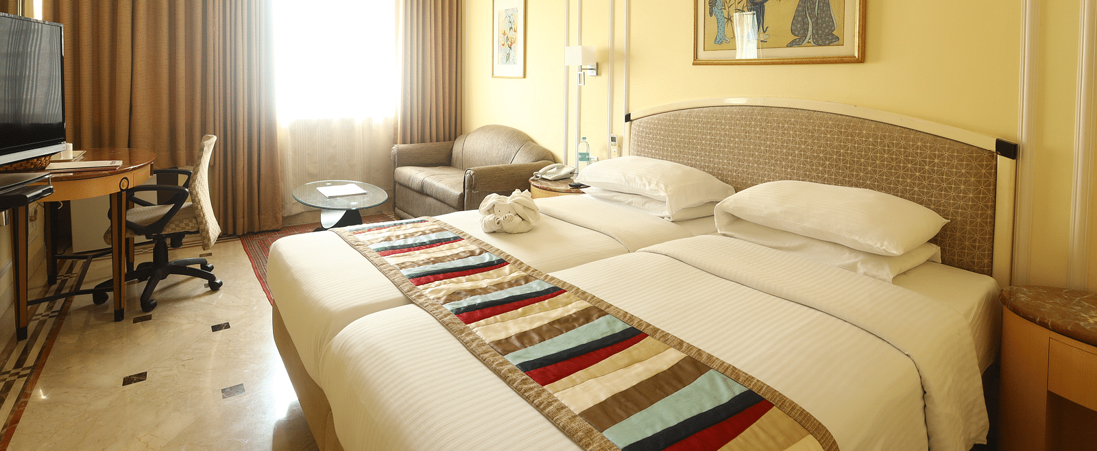 Twin beds in the Superior Room with sunlight peeking through the windows at Regency Hotel, Mumbai.
