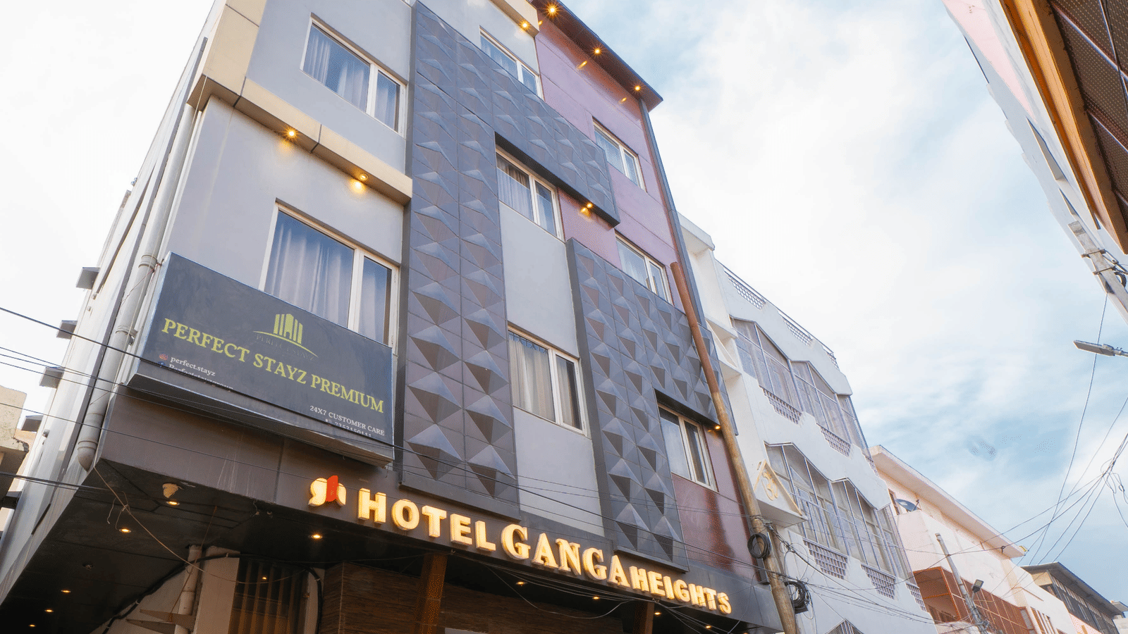 Exterior view of the multi-storey hotel building under a bright sky from a low angle - Perfectstayz Premium at Har Ki Pauri Road (Ganga Heights)