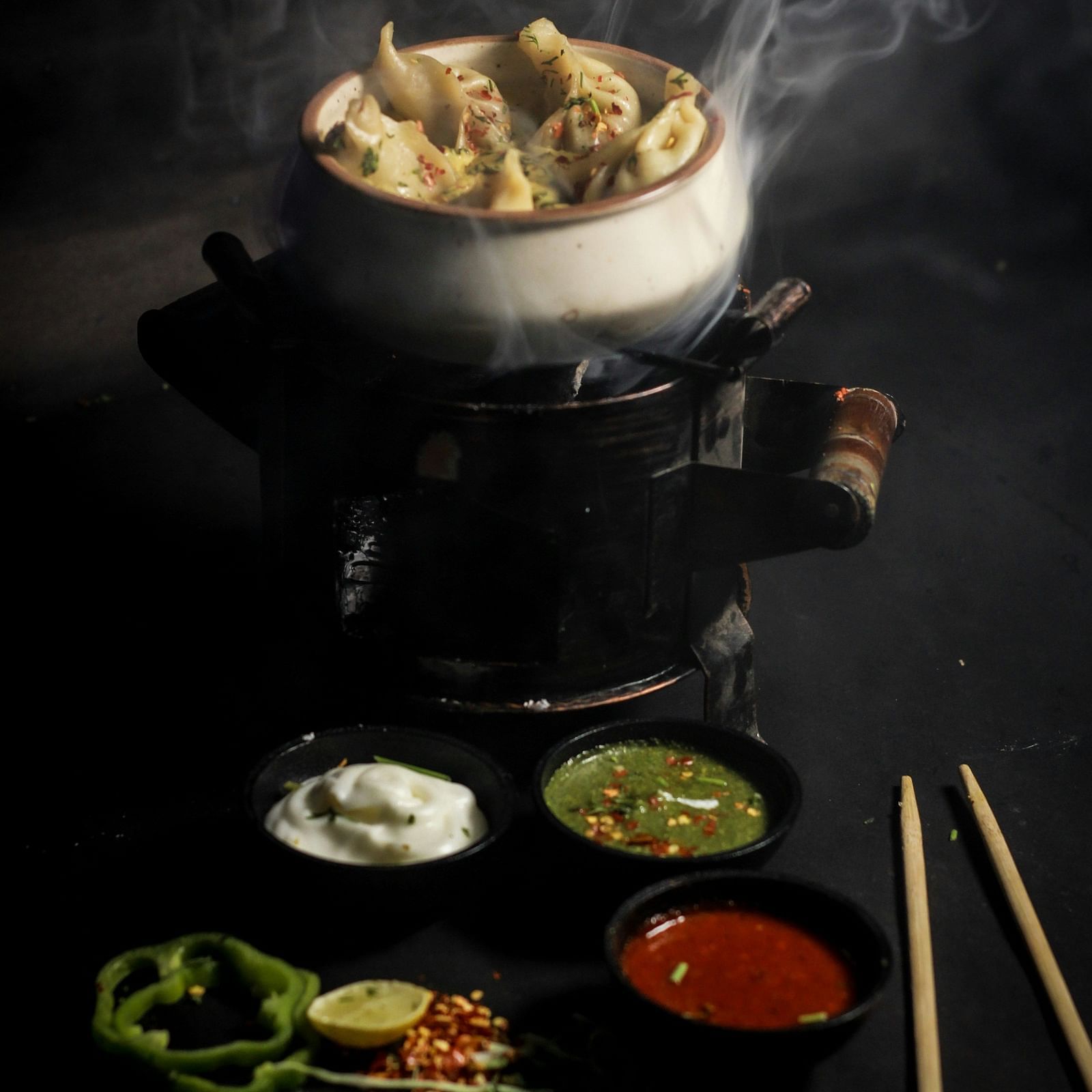 A plate of steaming hot momos with visible wisps of steam rising away.