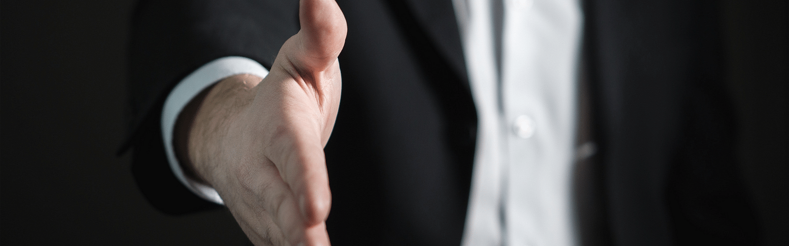 a person in a suit extending a handshake
