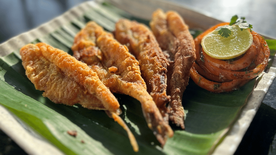 A plate of fried fish served on a banana leaf with a lime wedge at Oceanature Resort, Alibaug.