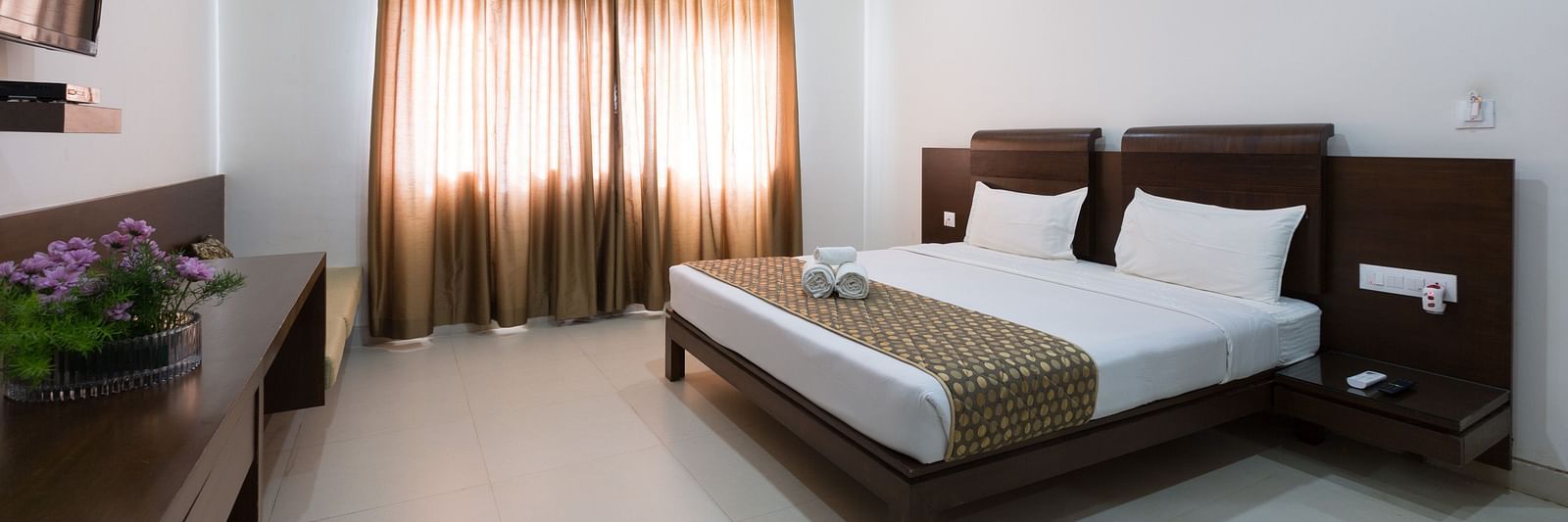 A bedroom with a bed, wooden furniture, and neutral-toned decor under soft lighting - Sanctum Suites BEL Road, Bangalore