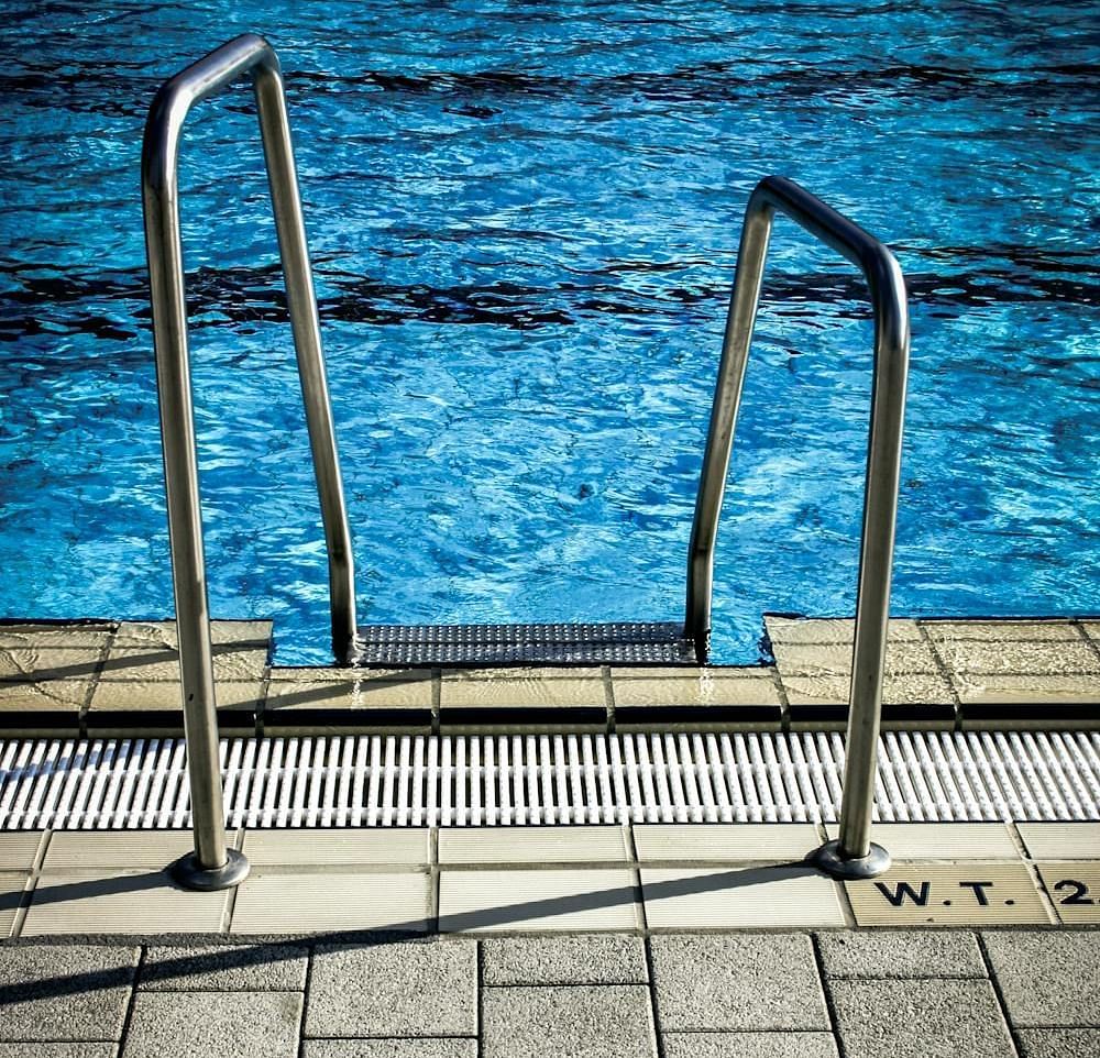 A swimming pool with metal stairs leading to the crystal clear water.