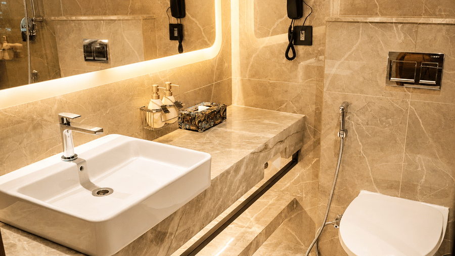 Modern bathroom at Pride Premier Pune with a marble vanity, wall mirror, toilet and contemporary fittings.