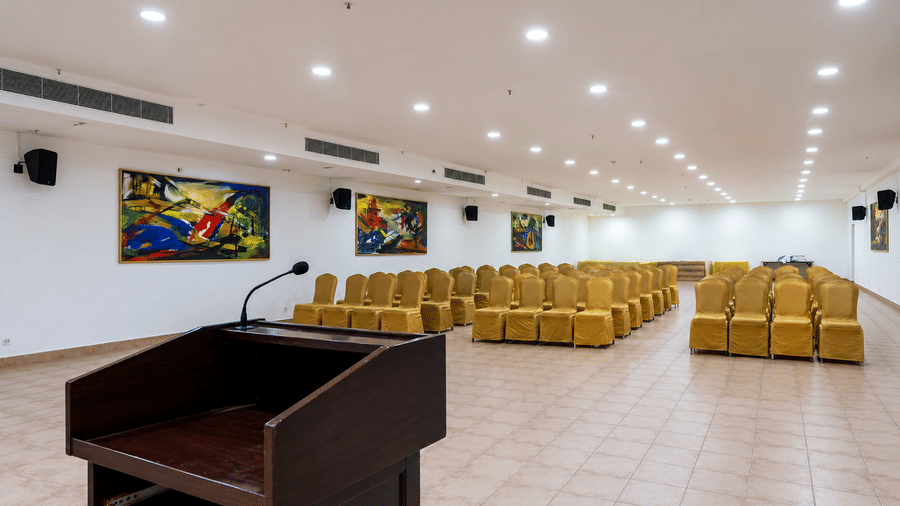 Orchid Hall featuring a podium with microphone and gold chairs at Chariot Beach Resorts, well-suited for presentations and events.