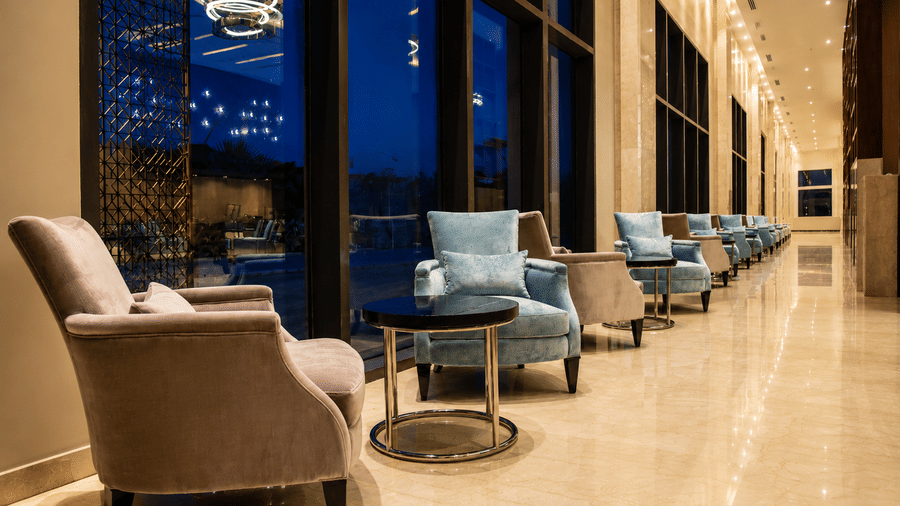 Plush lounge seating arranged along floor-to-ceiling windows at Kiranshree Grand Hotel.