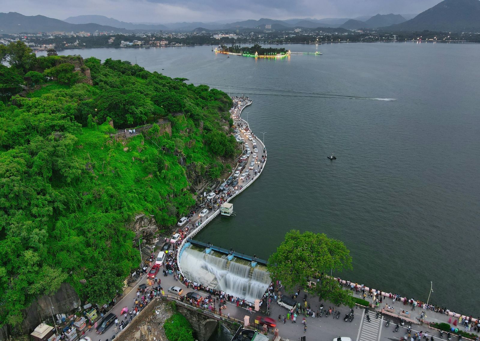 An aerial view of a solitary Fateh Sagar Lake Boat Ride with an island in the centre and greenery all around.