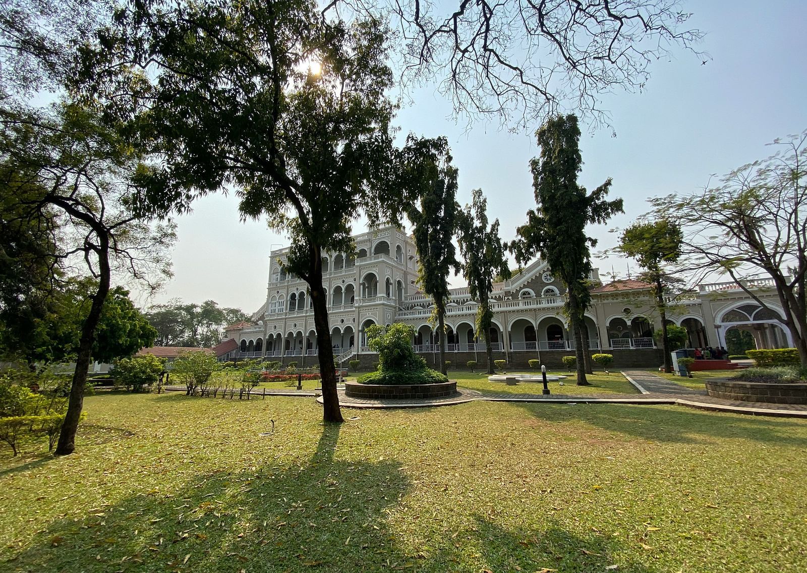 A far out view of Aga Khan Palace with a manicured garden in front of it.