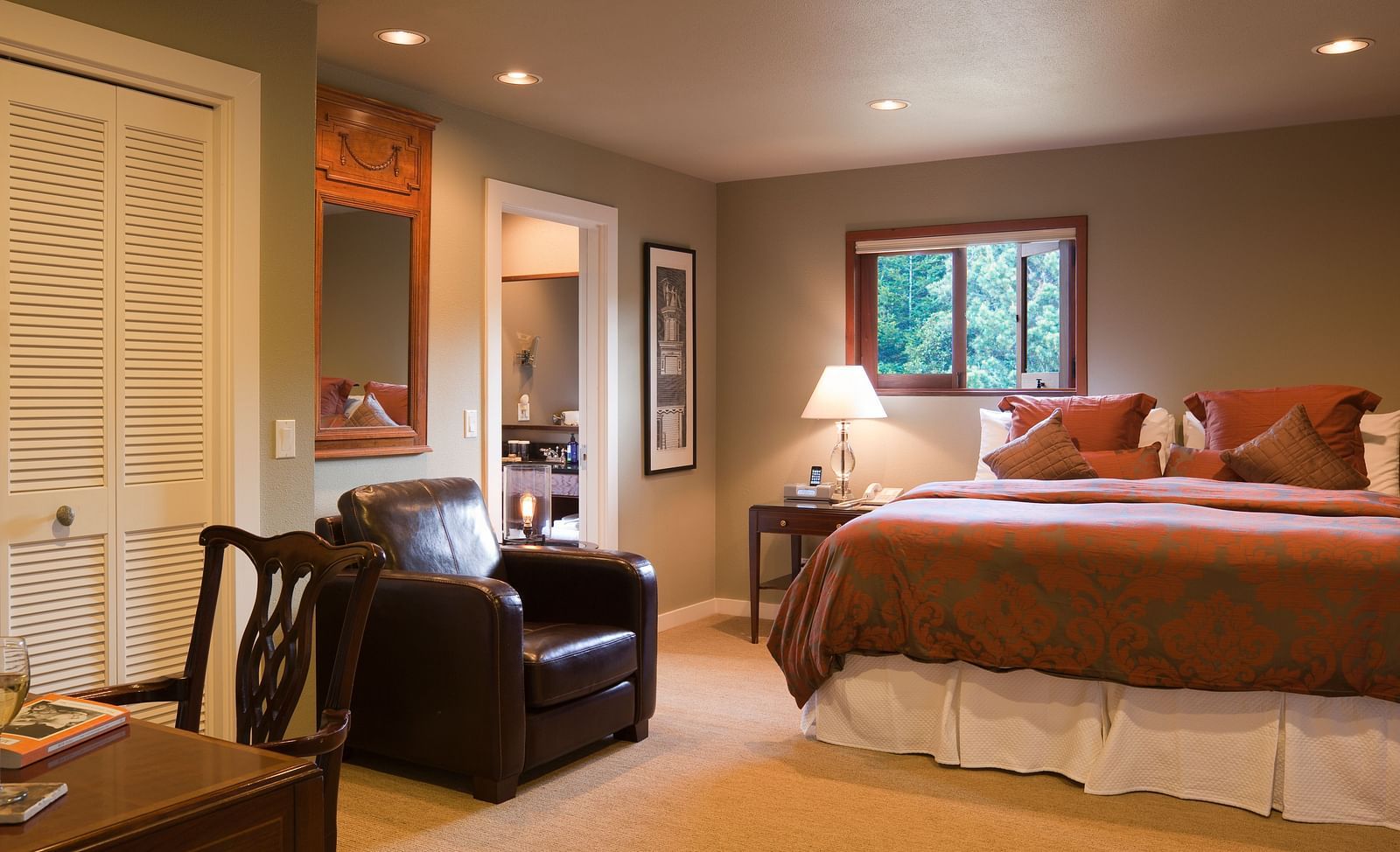 A view of Meadowview suite featuring a leather couch, a plush bed, and a night stand with lamp - Brewery Gulch Inn & Spa