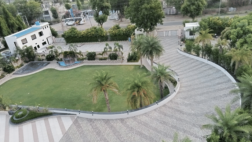 An aerial view of the Arawali Ananta Elite Jaipur hotel property with a winding paved path, a grassy lawn, and several buildings.