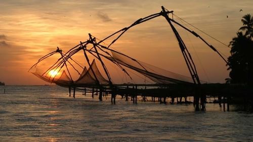 Chinese fishing nets being used during sunset to catch fish