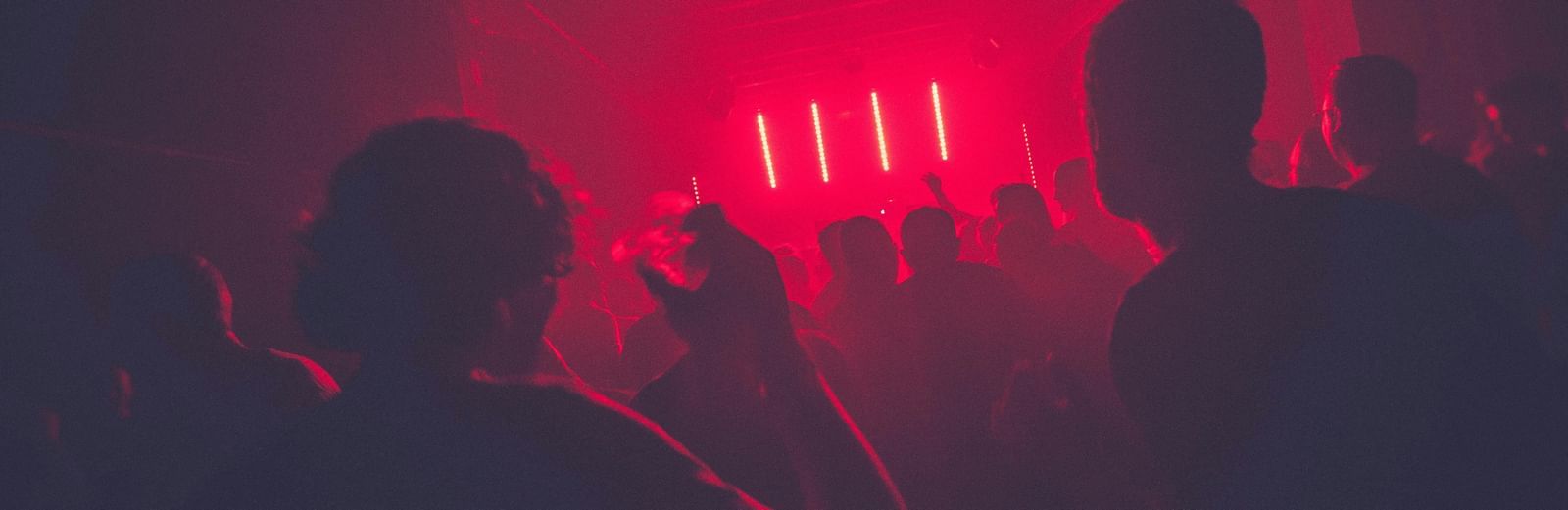 A view from inside a club with red tint and hues and silhouettes of people for the perfect Nightlife in Jamaica.