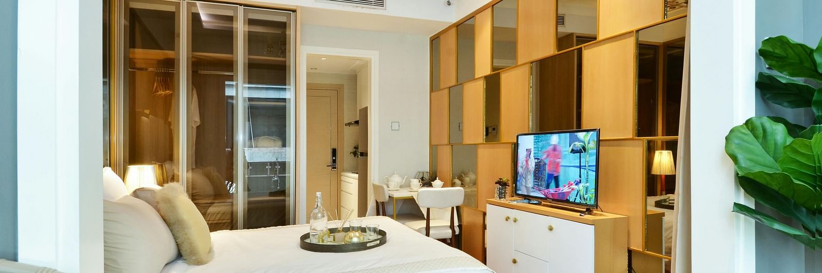 A hotel room featuring a double bed, television, bright lighting and wooden flooring.