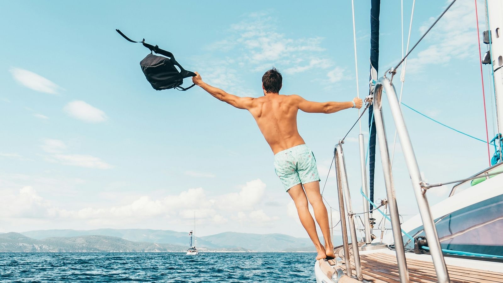 a person hanging on to the railings of a boat while it is travelling on water