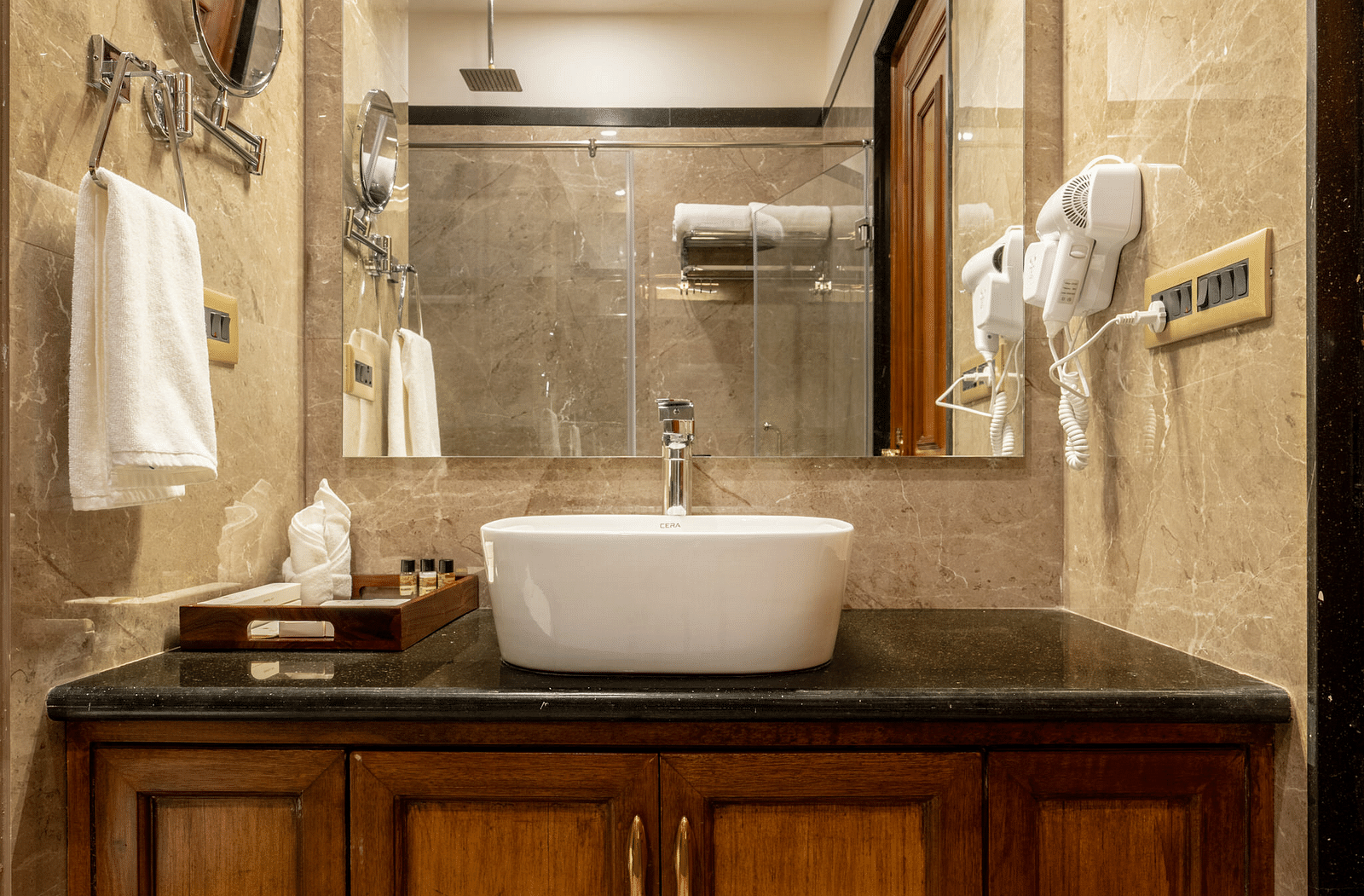 a wash basin with a covered vanity area along with a huge square shaped mirror - Brij Castle, Jaipur