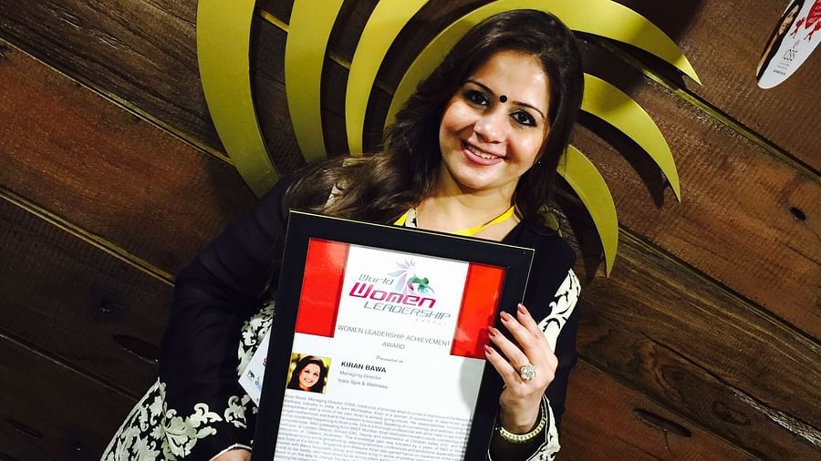 Kiran Bawa holding a framed picture in front of IOSIS Spa & Wellness