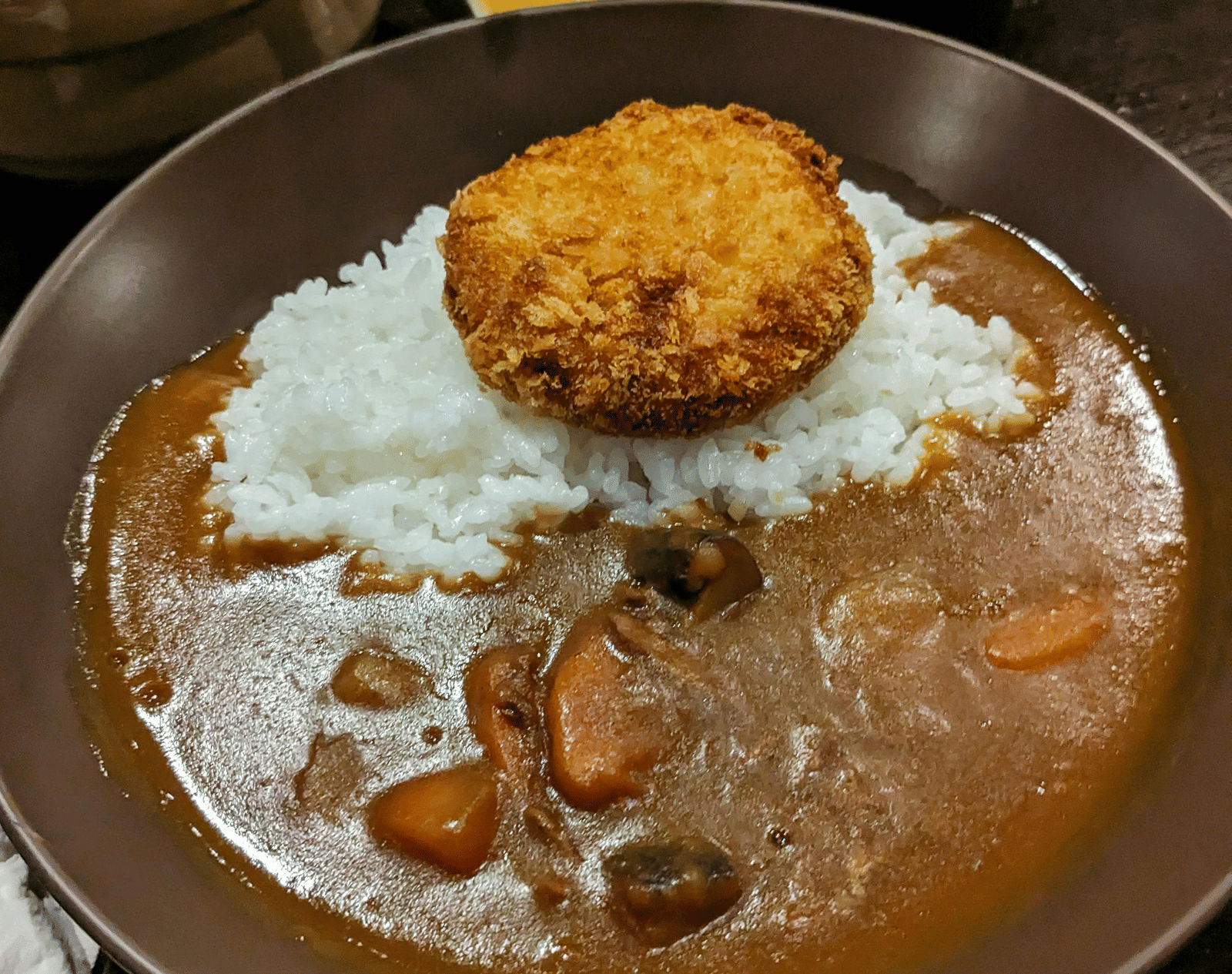 A plate of curry with rice and vegetables, served with a side of salad and chutney.