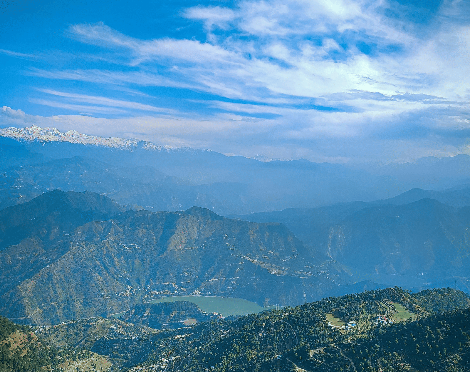 A panoramic view of a mountain range with a clear blue sky and some clouds.
