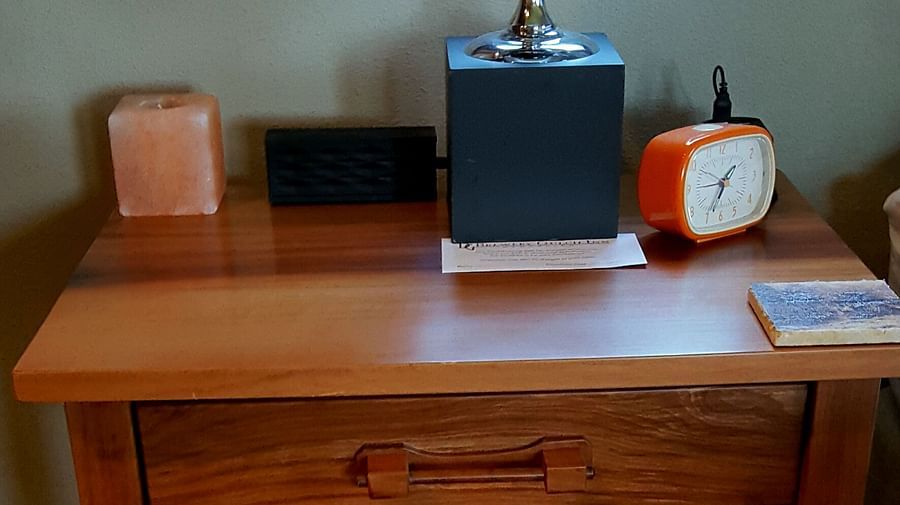 A stylish wooden desk featuring an alarm clock, a scented candle, and a perpetual motion desk toy - Brewery Gulch Inn & Spa