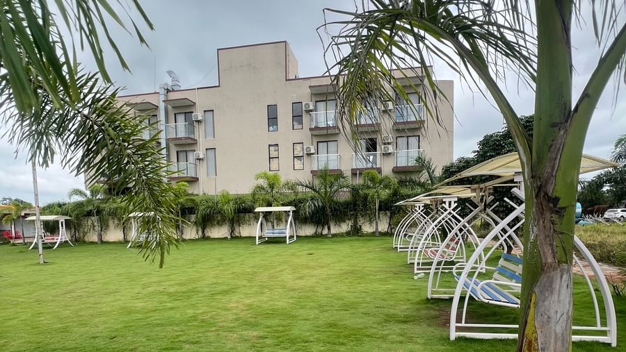 Expansive view of the lawn and multi-storey structure of Daksh The Valley Resort, Saputara, as seen on a cloudy area.