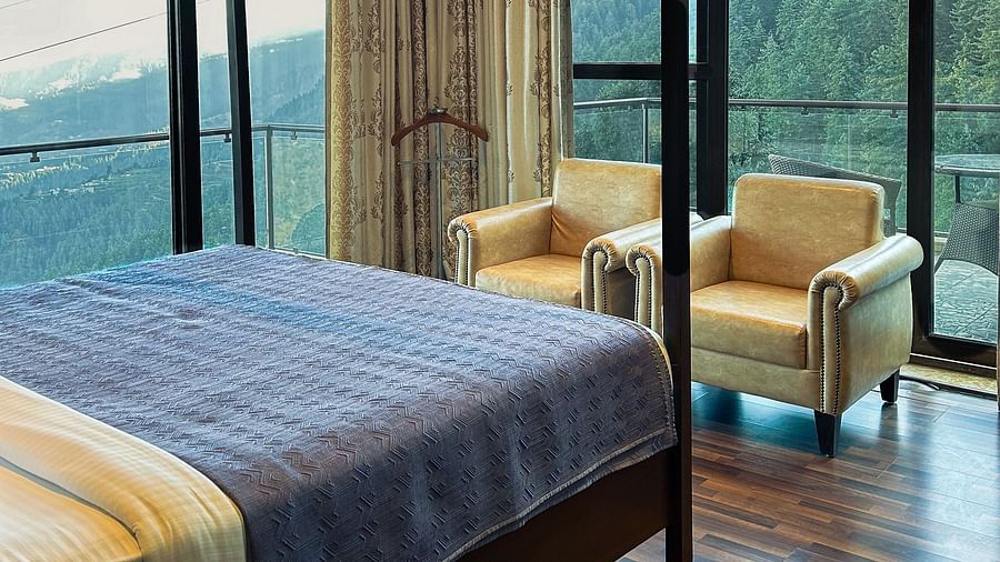 Luxury bedroom with floor-to-ceiling windows and forest views at Aranya Himalayan Retreat in Mashobra