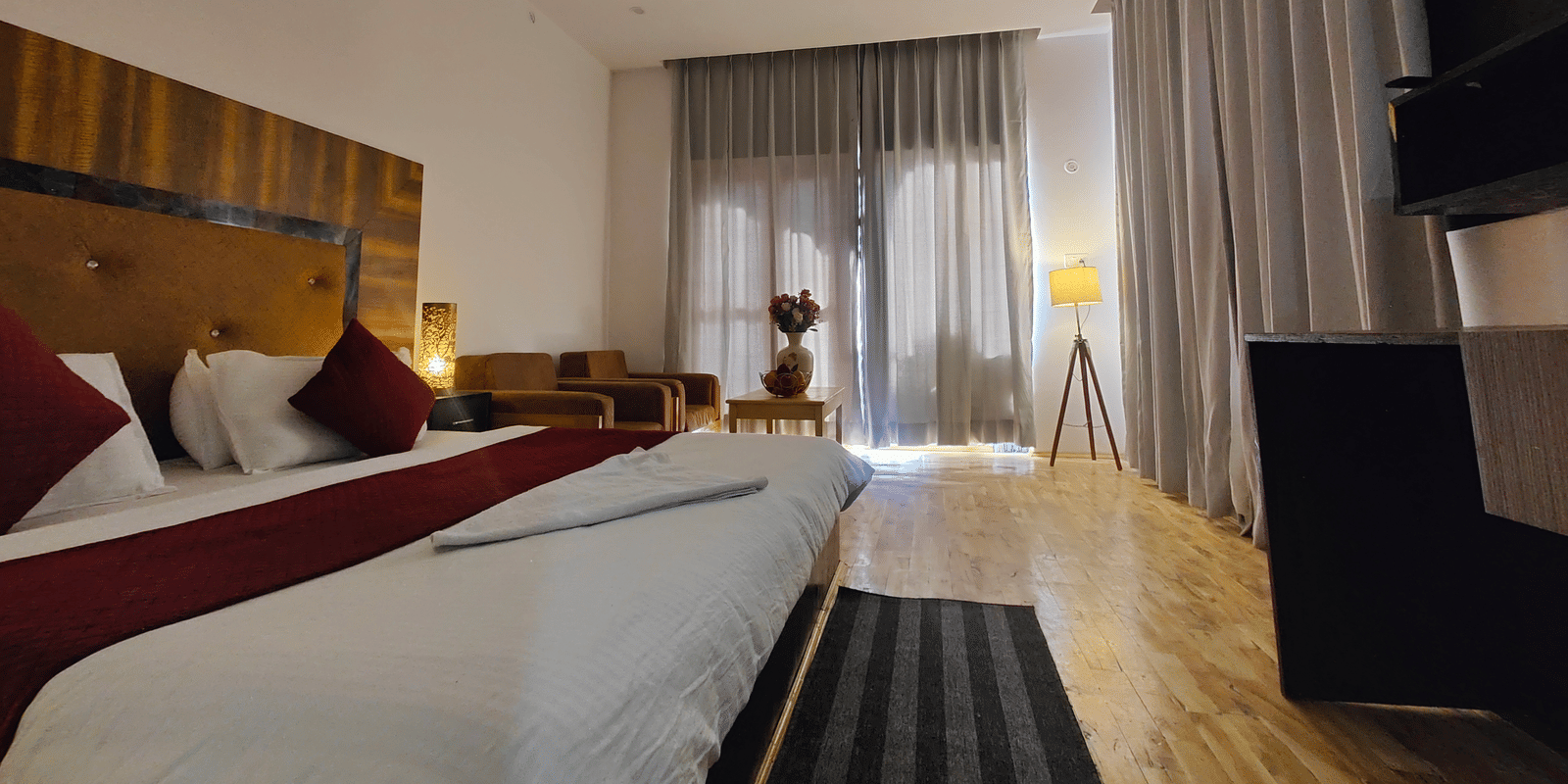 A bright bedroom featuring a large bed and glass doors leading to a private balcony at Indus Serenity Retreat.