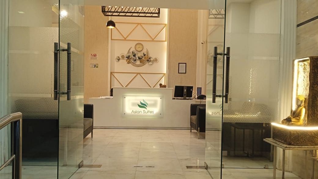 A modern entrance with glass doors and decorative wall panels leads into a brightly lit interior space - Asian Suites Cyber Park, Gurgaon