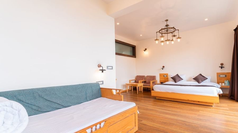 A bedroom with a bed, a couch, and a television, warm lighting, interior setting - Clarks Exotica Resort, Near Mukhteshwar.