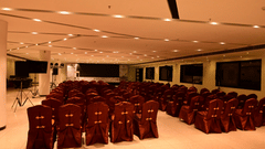 A large conference hall at Arawali Ananta Elite Jaipur with rows of red chairs and a stage.