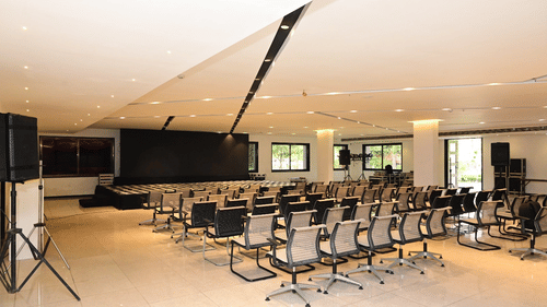 A seminar room at Arawali Ananta Elite Jaipur with a projection screen and white chairs arranged in rows.