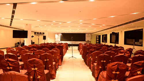 A large conference room with rows of red chairs facing a stage at Arawali Ananta Elite Jaipur