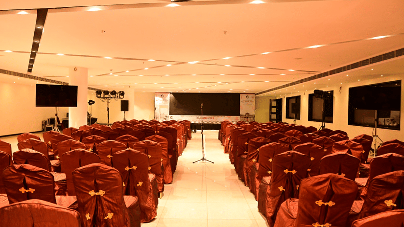 A large conference room with rows of red chairs facing a stage at Arawali Ananta Elite Jaipur