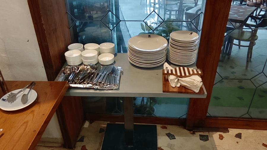 A table laid out with neatly organised stacks of cutlery, beside a glass wall with seating arrangements in the background | Kings International Juhu