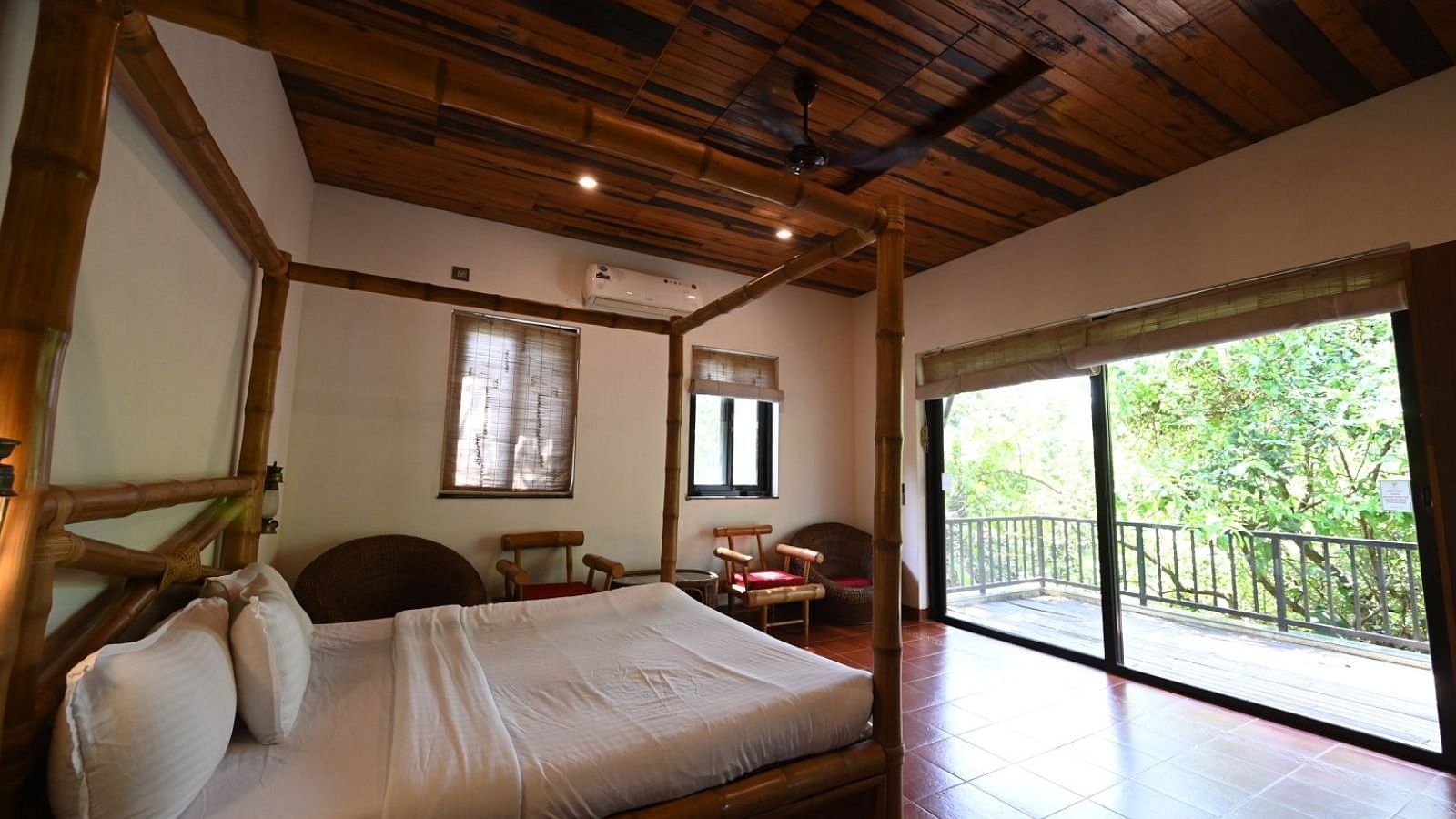 A bedroom with a wooden four-poster bed, white linens, and large windows.