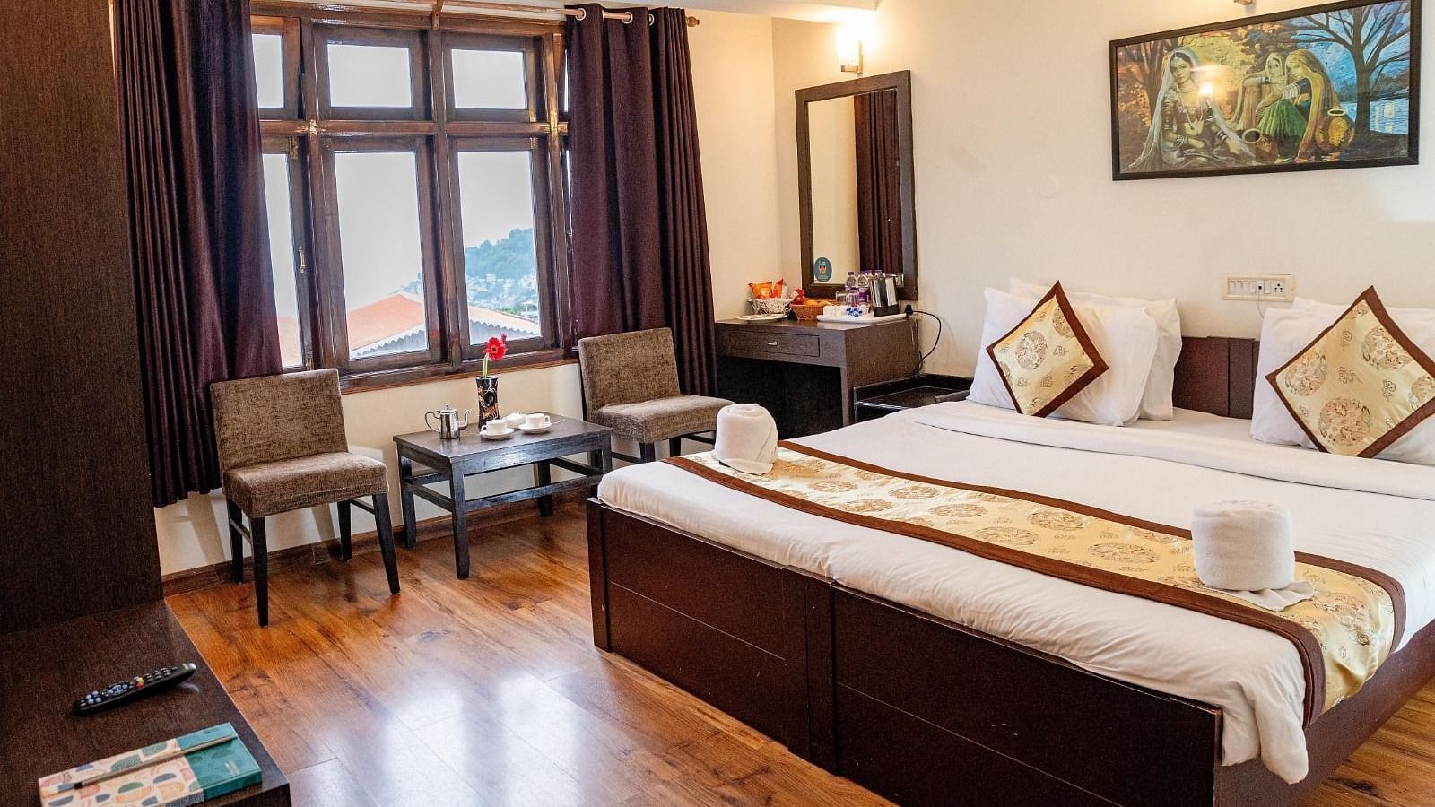 A Premium Room featuring a double bed along with two arm chairs placed in front of a window at Sumitel Sanderling.