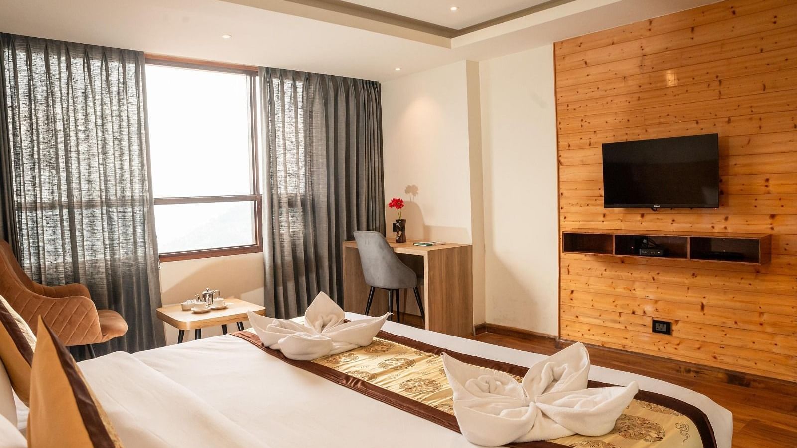 A wall-mounted television with a double bed placed opposite to it in a Premium Room at Sumitel Sanderling.