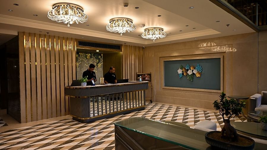 Reception area featuring a front desk with an individual assisting, illuminated by hanging ceiling lights at BluSalzz Residence, Amritsar.
