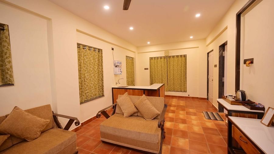 A well-lit room with a tan couch, a small table, dark wood trim, and a ceiling fan.