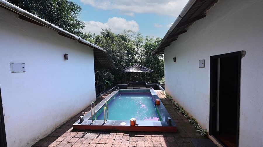 A swimming pool with blue tiles, surrounded by a patio and white walls.