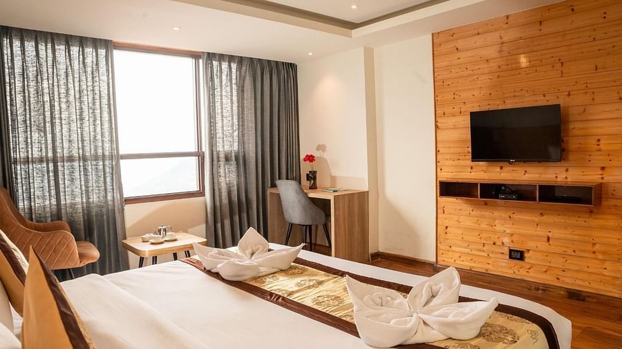 A wall-mounted television with a double bed placed opposite to it in a Premium Room at Sumitel Sanderling.