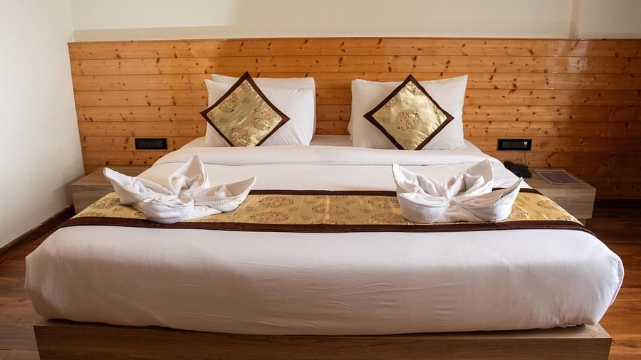 Front view shot of a double bed with well-arranged pillows and cushions along with two bed side tables on either side of the bed at Sumitel Sanderling.