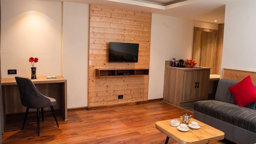 A wall-mounted television with a common seating area in front of it along with a small coffee table in the Suite of Sumitel Sanderling.
