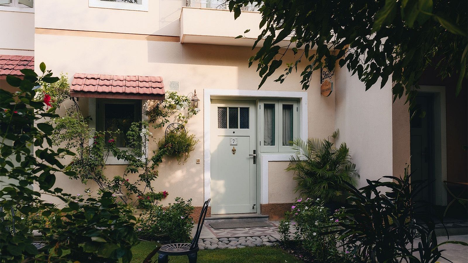 The exterior of a Karma Chalets unit with a small lawn, trees, and patio furniture.